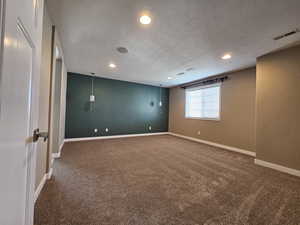 Carpeted empty room featuring a textured ceiling