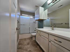 Full bathroom featuring vanity, toilet, and enclosed tub / shower combo