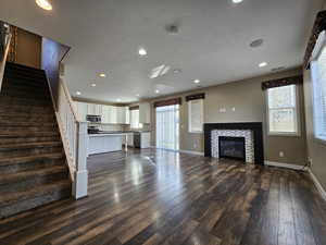 Unfurnished living room with a tiled fireplace, dark hardwood / wood-style flooring, and a textured ceiling