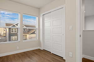 Unfurnished bedroom with multiple windows, a closet, and dark hardwood / wood-style floors