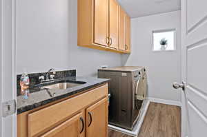 Laundry area featuring sink, cabinets, a textured ceiling, washing machine and clothes dryer, and dark hardwood / wood-style floors