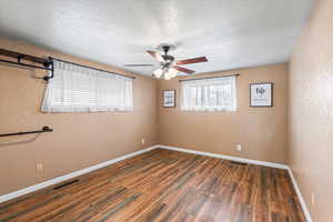 Primary room featuring a textured ceiling, dark hardwood / wood-style floors, and ceiling fan