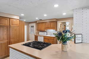 Kitchen with gas cooktop, a textured ceiling, dishwasher, and sink