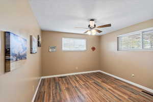 Bedroom with ceiling fan, a healthy amount of sunlight, a textured ceiling, and wood-type flooring