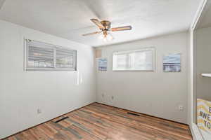 Den with ceiling fan, dark wood-type flooring, and a textured ceiling