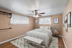 Virtually staged. Primary bedroom with hardwood / wood-style floors, ceiling fan, and a textured ceiling