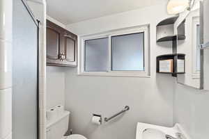 Bathroom featuring sink, an enclosed shower, and toilet