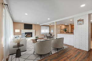 Virtually Staged. Living room featuring brick wall, light hardwood / wood-style floors, and a textured ceiling