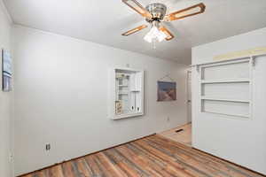 Den featuring hardwood / wood-style floors, ceiling fan, crown molding, and a textured ceiling