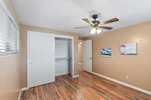 Bedroom with a closet, ceiling fan, and dark wood-type flooring