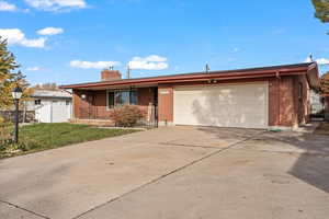 Single story home with a front yard, a garage, and covered porch