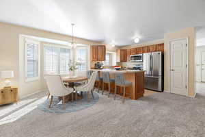 Dining space featuring light colored carpet, a textured ceiling, and an inviting chandelier