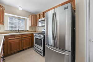 Kitchen with appliances with stainless steel finishes, a textured ceiling, and sink