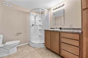 Bathroom featuring vanity, a textured ceiling, toilet, and an enclosed shower