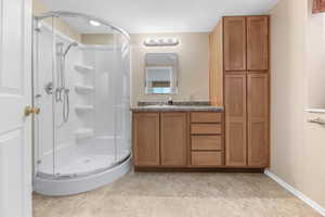 Bathroom with vanity, a shower with shower door, and a textured ceiling