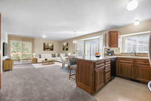 Kitchen featuring sink, decorative light fixtures, kitchen peninsula, dishwasher, and light carpet