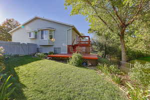 Rear view of house with a lawn and a wooden deck