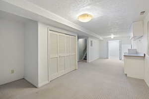 Hall featuring light carpet and a textured ceiling