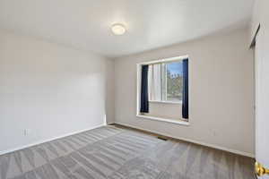 Carpeted spare room with a textured ceiling