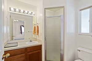 Bathroom featuring vanity, toilet, and an enclosed shower