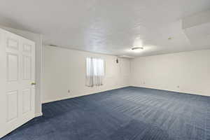 Basement featuring dark colored carpet and a textured ceiling