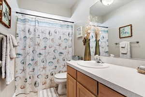 Bathroom featuring curtained shower, vanity, and toilet