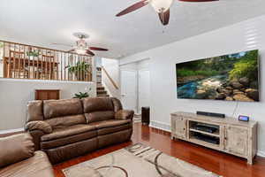 Living room featuring a textured ceiling, dark hardwood / wood-style floors, and ceiling fan