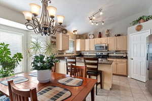 Tiled dining area with a textured ceiling, lofted ceiling, a healthy amount of sunlight, and a notable chandelier