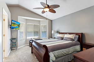 Bedroom with light colored carpet, lofted ceiling, and ceiling fan