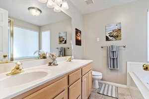 Bathroom featuring tile patterned flooring, vanity, a tub to relax in, and toilet