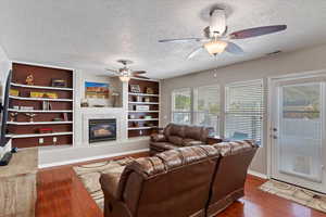 Living room with ceiling fan, dark hardwood / wood-style floors, and a textured ceiling