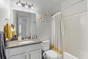 Full bathroom featuring vanity, shower / tub combo with curtain, and toilet