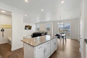 Kitchen featuring white cabinetry, a center island, an inviting chandelier, decorative light fixtures, and dark hardwood / wood-style floors