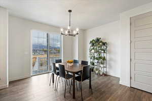 Dining area with a textured ceiling, dark hardwood / wood-style floors, and an inviting chandelier