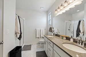 Bathroom with a shower with door, vanity, and toilet