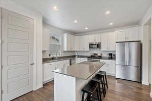 Kitchen featuring a center island, stainless steel appliances, white cabinetry, and dark hardwood / wood-style floors