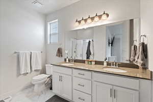 Bathroom with vanity, an enclosed shower, and toilet