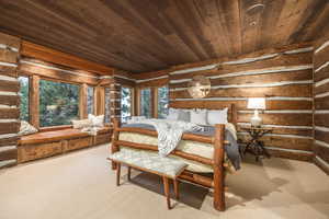 Carpeted bedroom with multiple windows and wood ceiling