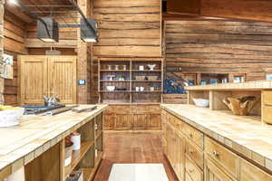 Kitchen with light hardwood / wood-style floors, rustic walls, and tile counters