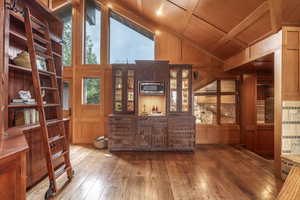 Office area featuring vaulted ceiling with beams, wood walls, hardwood / wood-style floors, and wooden ceiling