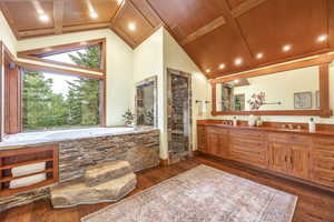 Bathroom featuring vaulted ceiling with beams, hardwood / wood-style floors, a bathtub, vanity, and wood ceiling