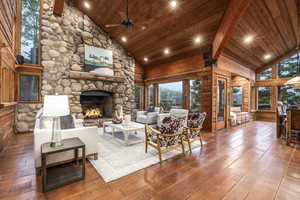 Living room with a fireplace, high vaulted ceiling, hardwood / wood-style flooring, and beamed ceiling