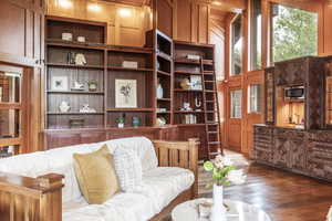 Living room with wooden walls, built in shelves, and hardwood / wood-style flooring