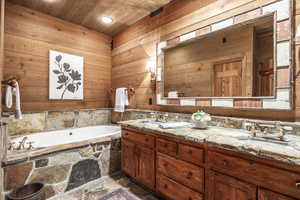 Bathroom with vanity, wooden ceiling, wood walls, and a tub