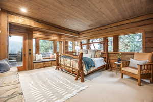 Bedroom featuring multiple windows, wooden walls, and wood ceiling