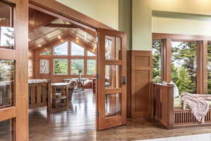 Foyer entrance featuring vaulted ceiling, hardwood / wood-style flooring, and wooden walls