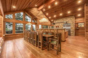 Dining area with beam ceiling, high vaulted ceiling, light hardwood / wood-style flooring, and wooden ceiling