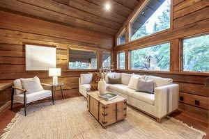 Living room with wood walls, high vaulted ceiling, wood ceiling, and light wood-type flooring