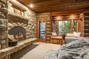 Carpeted bedroom with a fireplace, access to outside, multiple windows, and wood ceiling