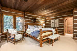 Bedroom with log walls, carpet floors, and wooden ceiling